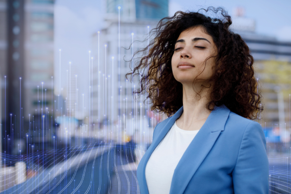 A woman standing with her eyes closed, with OpenBlue graphics and buildings in the background