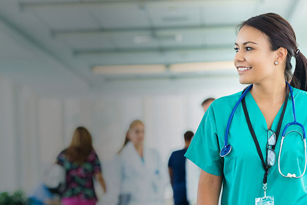 A medical professional in scrubs smiling with a stethoscope around her neck