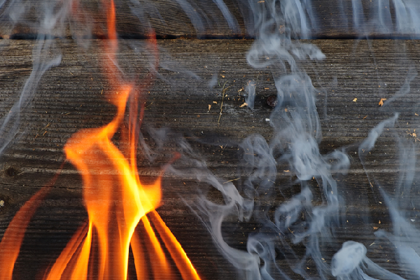 A piece of wood catching on fire with smoke