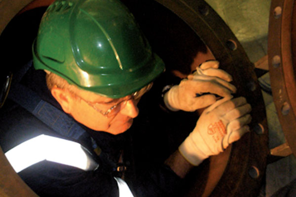 A man in safety gear coming out of a manhole cover